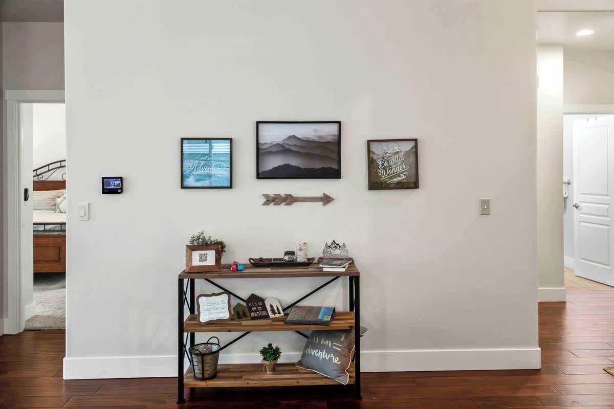 Un pasillo con una consola de madera que exhibe varios objetos decorativos y una pared con tres cuadros enmarcados.