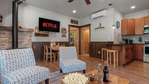 A living room with patterned sofas, a wooden coffee table with snacks, and a kitchen area with wooden cabinets. - Cozy Mountain Retreat Near Leavenworth w/ Private Patio + BBQ (Leavenworth)