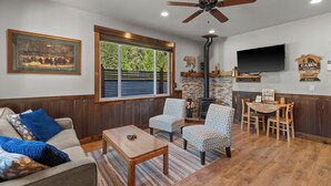 A living room with a sofa, two patterned chairs, a coffee table, a fireplace, a television, and a ceiling fan. - Cozy Mountain Retreat Near Leavenworth w/ Private Patio + BBQ (Leavenworth)