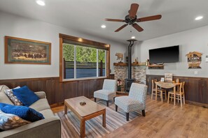 A living room with a sofa, two patterned chairs, a coffee table, a fireplace, a television, and a ceiling fan. - Cozy Mountain Retreat Near Leavenworth w/ Private Patio (Leavenworth)