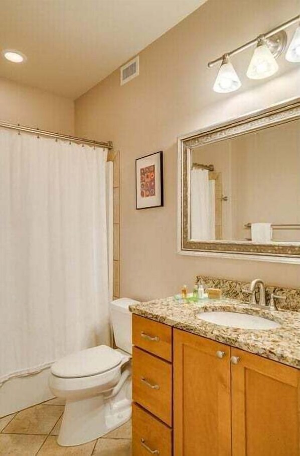 A bathroom with a toilet, sink, vanity, and a shower curtain. - Walkable Leavenworth Condo w/ King Suite (Leavenworth)