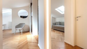 A modern interior with a herringbone wooden floor, a grey chair, a grey sofa, and a skylight. - Asisium Boutique Hotel (Assisi)