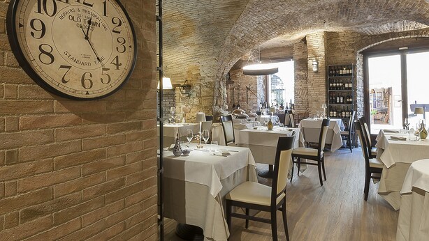 A restaurant with brick walls, wooden floors, and tables set for dining. - Asisium Boutique Hotel (Assisi)