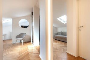 A modern interior with a herringbone wooden floor, a grey chair, a grey sofa, and a skylight. - Asisium Boutique Hotel (Assisi)