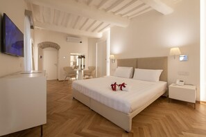 A hotel room with a bed, bedside table, and a TV. - Asisium Boutique Hotel (Assisi)