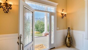 Une porte avec un panneau de verre, un paillasson et un vase.