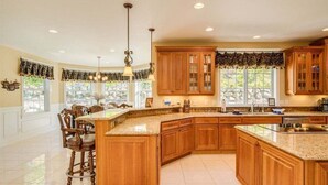 Une cuisine spacieuse avec des meubles en bois, un grand îlot central et des luminaires suspendus.