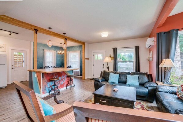 A cozy living room with a sofa, coffee table, and a small bar area with stools.