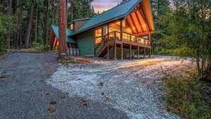 Une cabane avec un toit en pente, une terrasse en bois et une allée gravillonnée.