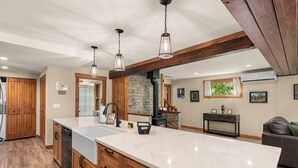 Une cuisine avec des meubles en bois, un plan de travail en marbre et des luminaires suspendus.