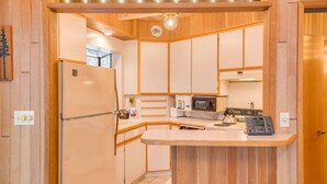 A compact kitchen with a refrigerator, microwave, kettle, and a small island counter. - Octagon House Near Leavenworth + Deck (Leavenworth)