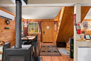 Een gezellig chaletinterieur met een houtkachel, een eethoek en een keuken met een koelkast.