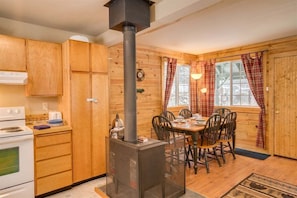 A wooden interior with a kitchen stove, dining table, chairs, and a fireplace. - The Haven - A Pleasant and Pleasing Adventure Pad (Leavenworth)