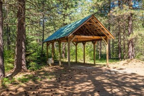 Puinen huvimaja, jonka katto on vihreä, sijaitsee metsäisellä alueella.
