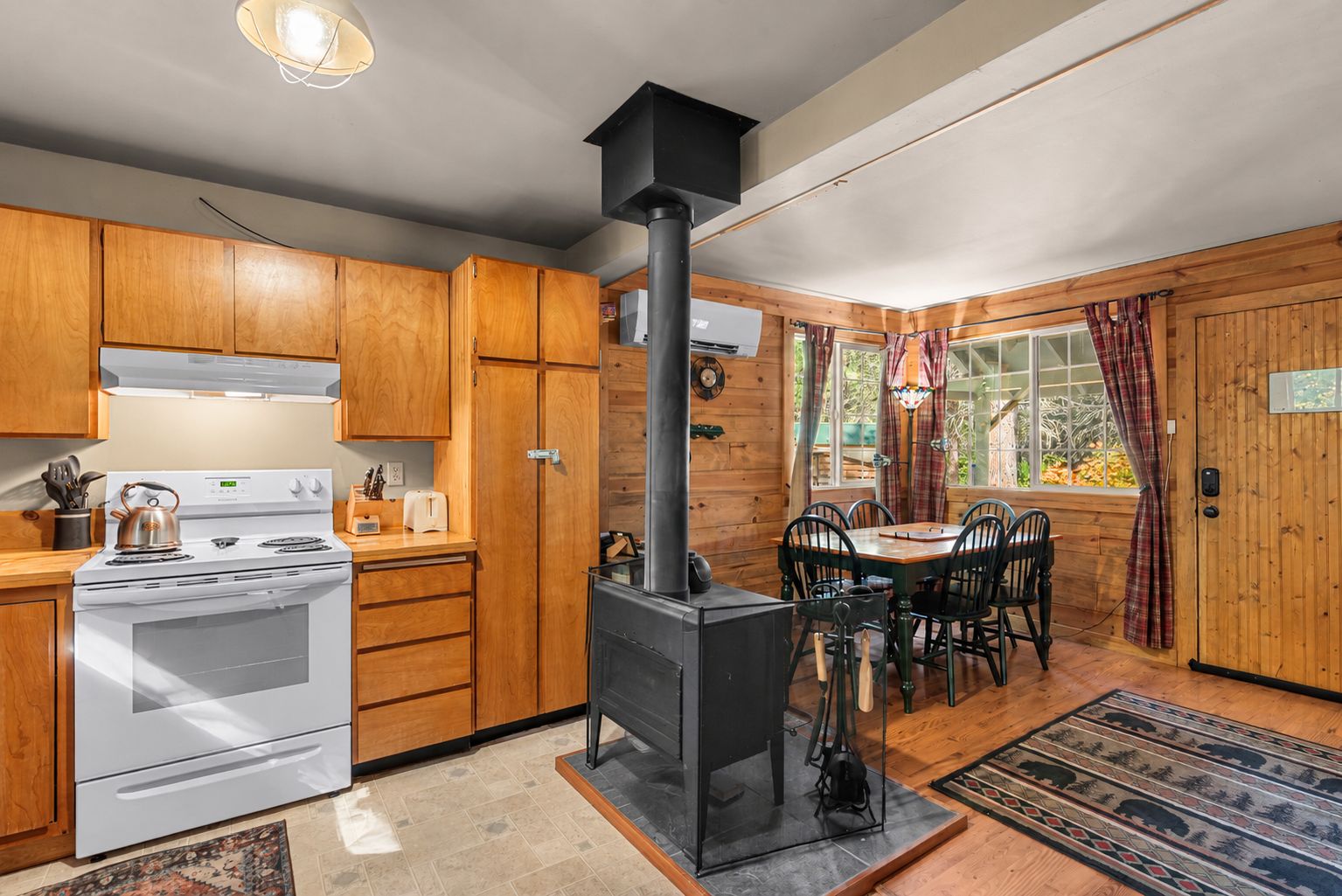 A kitchen with wooden cabinets, a stove, and a wood-burning stove.