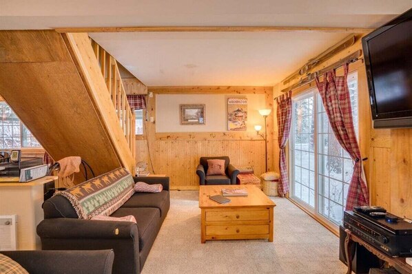 A cozy cabin interior with a sofa, a coffee table, a television, and a window with curtains. - The Haven - A Pleasant and Pleasing Adventure Pad (Leavenworth)