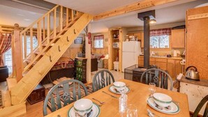 A wooden interior with a dining table set for two, a staircase, and a kitchen area. - Cozy 2BR cabin in Plain/Lake Wenatchee with fireplace, AC, and parking. Pet-friendly (Leavenworth)