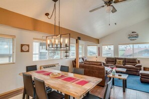 A spacious living area with a dining table, a sofa, and a ceiling fan.