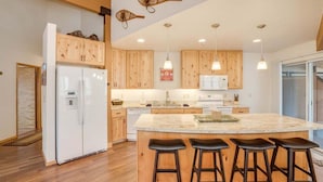 Una cucina moderna con mobili in legno, un'isola centrale con sgabelli, un frigorifero e luci a sospensione.