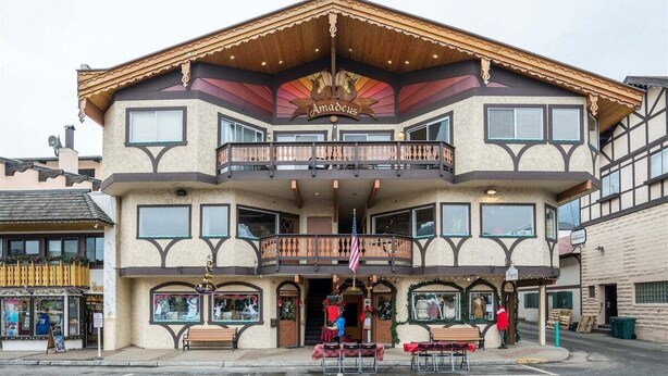 A two-story building with a balcony, a sign reading 'Amadeus,' and a storefront with a Christmas display.