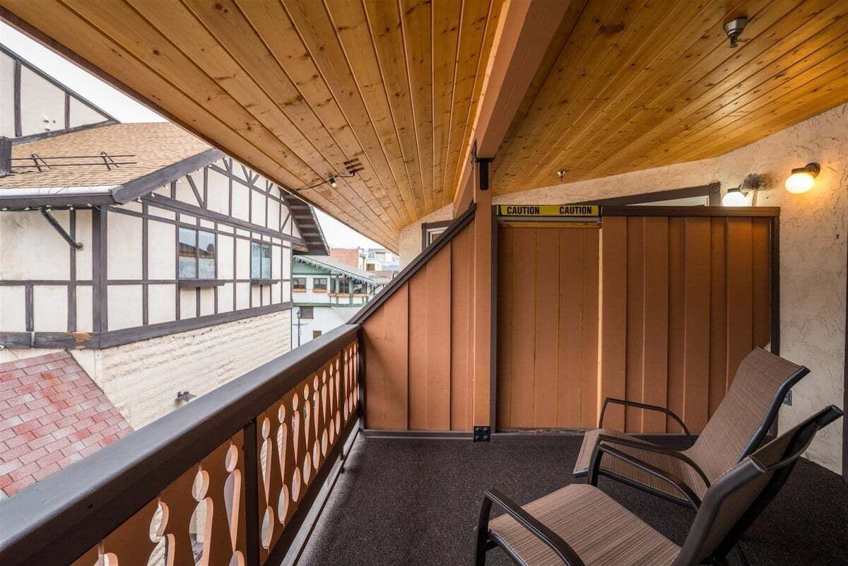 A balcony with wooden railings, a caution sign, and a chair.