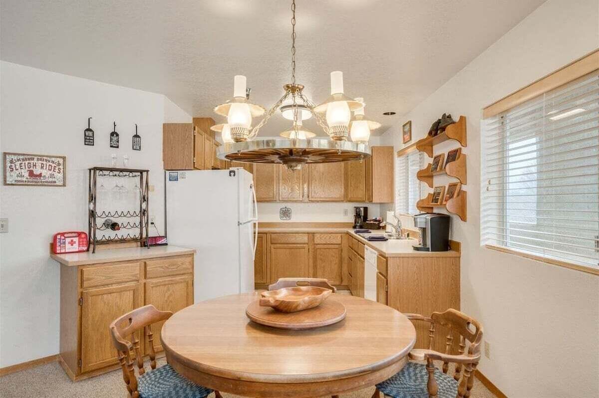 A compact kitchen with wooden cabinets, a central island, and a chandelier.