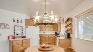 A compact kitchen with wooden cabinets, a central island, and a chandelier.