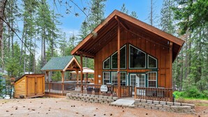 A wooden cabin with large windows, a covered porch, and a gravel driveway. - 2BR cabin in Leavenworth with hot tub, fireplace, BBQ, 2 kings (Leavenworth)