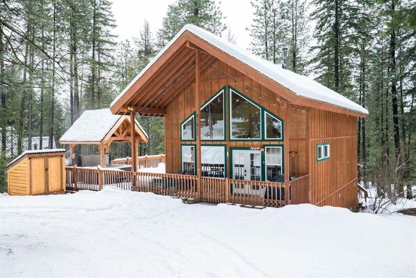 A wooden cabin with large windows, a porch, and a snow-covered roof. - Base Camp Lodge - First-Rate Adventure Base (Leavenworth)