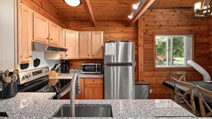 A kitchen with granite countertops, stainless steel appliances, wooden cabinets, and a window. - Sunrise Lodge - Fetching Forest Cabin in the Sun! (Leavenworth)