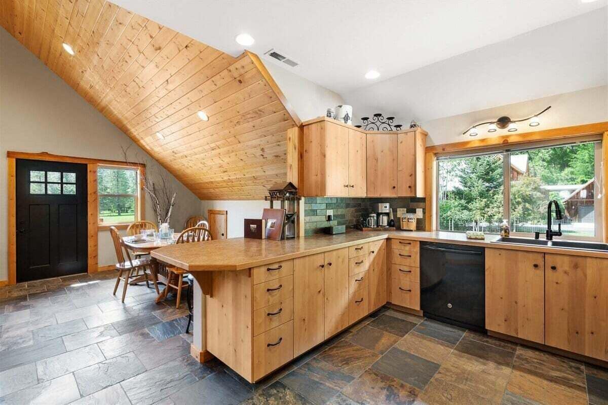 A kitchen with wooden cabinets, a dining table, and a large window.