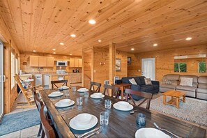 Interior de una cabaña de madera con comedor, cocina y sala de estar.