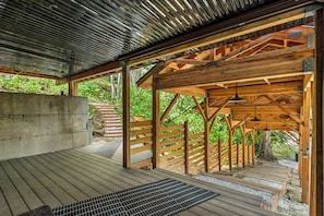 A covered wooden structure with a concrete wall, wooden deck, and metal roof.