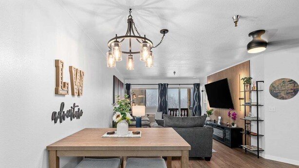 Uma sala de estar moderna com área de jantar, um candelabro e uma TV de tela plana.