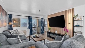 A modern living room with a sofa set, a coffee table, a flat-screen TV, and a wooden accent wall.