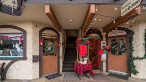 A building entrance with a staircase, a table with a red checkered tablecloth, and signs for a Renaissance Cafe and a boutique.