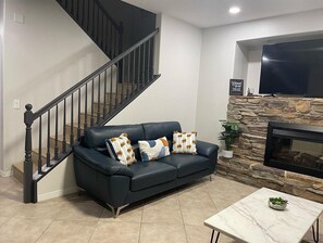 Relax in this stylish living room with a leather sofa, stone fireplace, and flat-screen TV.