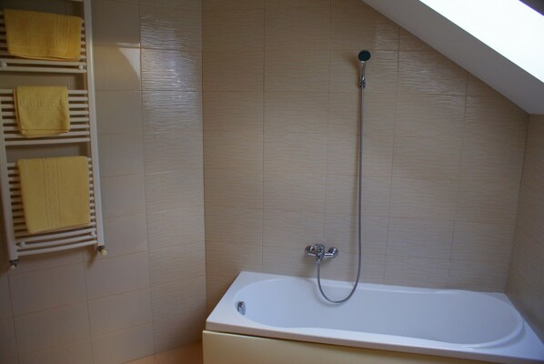 Une salle de bain équipée d’une baignoire, d’une douche et d’un porte-serviettes avec des serviettes jaunes.