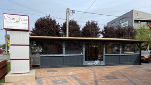 Un restaurant doté d’une terrasse couverte, d’une enseigne et d’une entrée pavée.