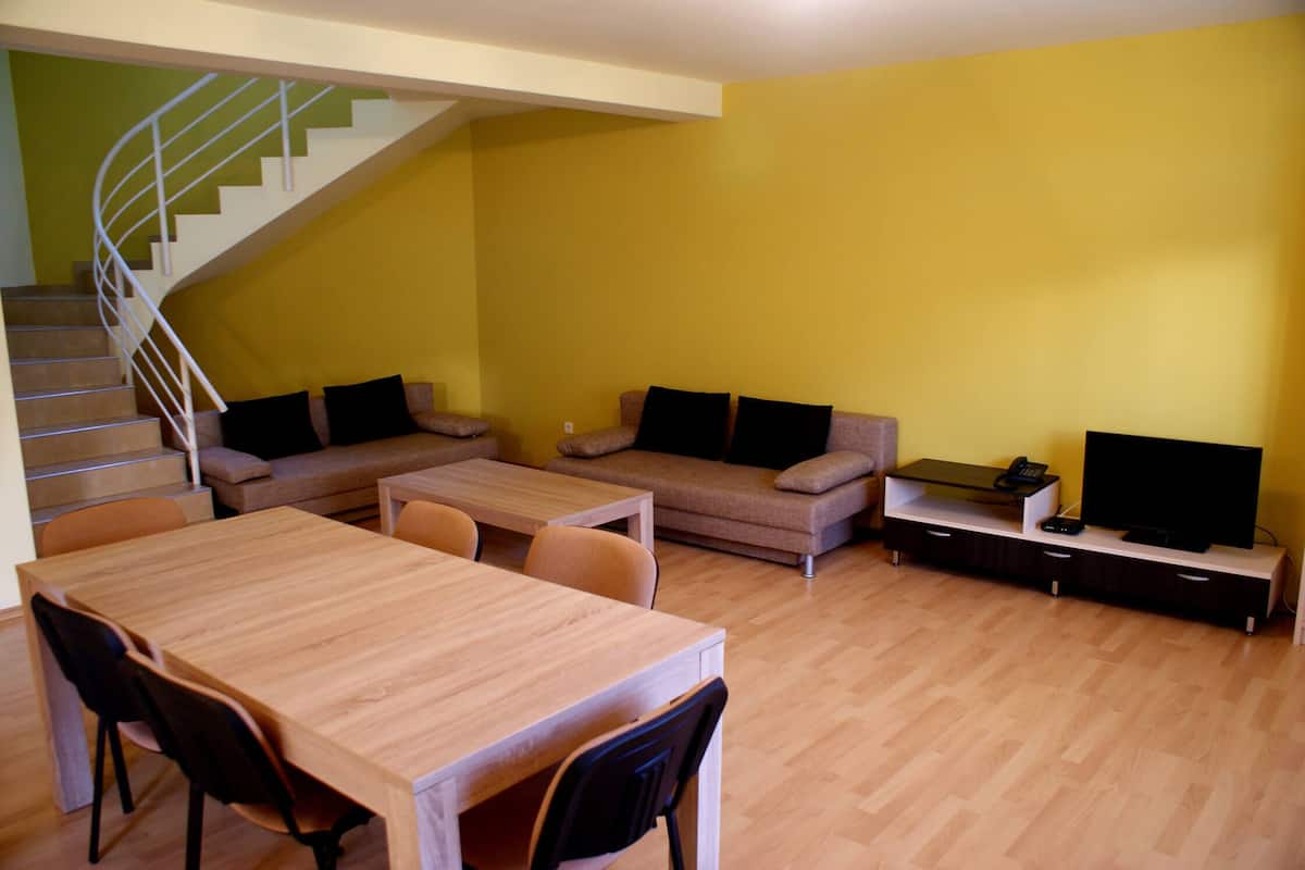 Uma sala de estar com escada, mesa de jantar e um conjunto de sofás.