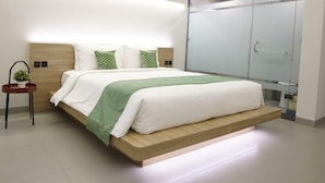 A modern bedroom with a bed, bedside table, and a green plant. - Qubika Boutique Hotel (Gading Serpong)