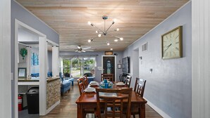Zona pranzo con tavolo in legno, sedie e una ventola a soffitto.