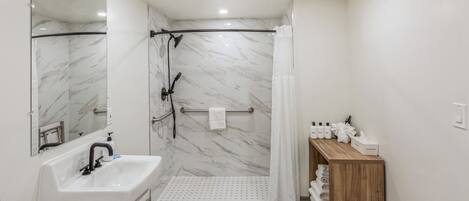 A modern bathroom with a shower, a sink, and a vanity with toiletries.