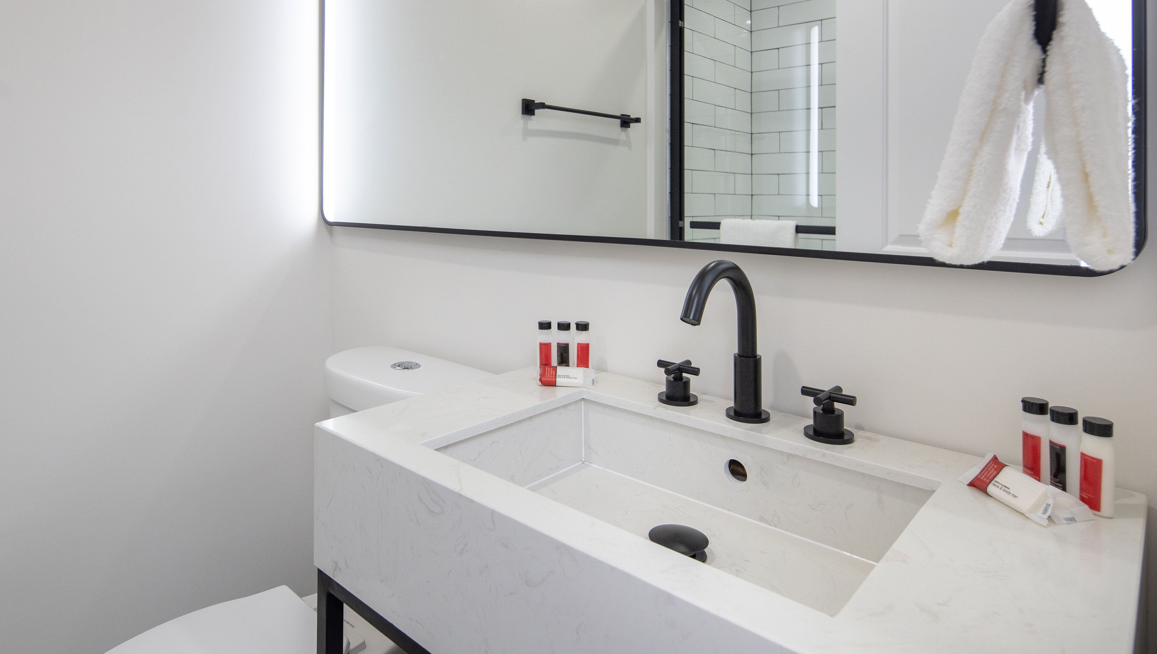 A modern bathroom with a white sink, black faucet, and a mirror above it.