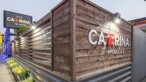 A wooden facade of The Catalina Hotel with illuminated signage. - The Catrina Hotel (San Mateo)