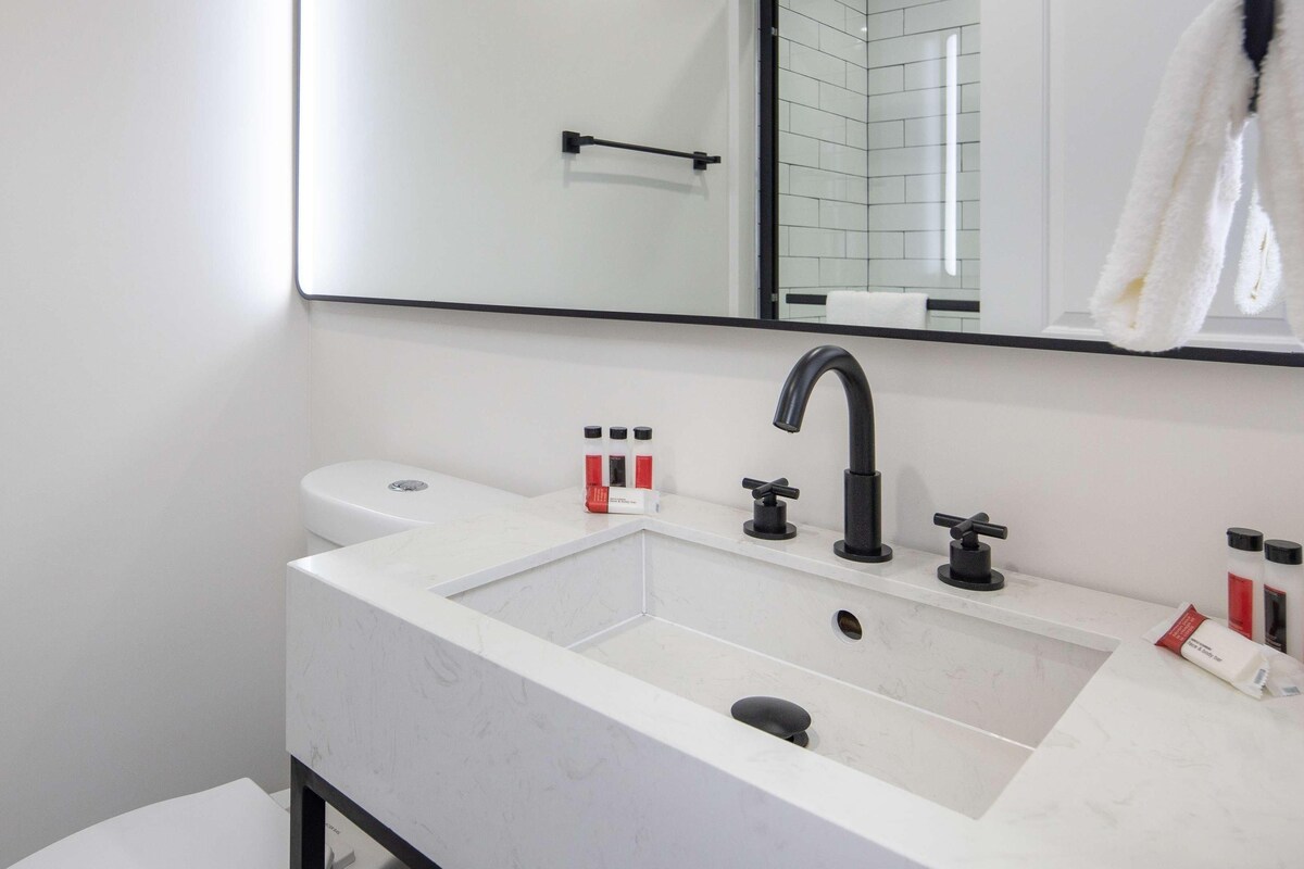 Une salle de bain moderne avec un lavabo blanc, un robinet noir et deux distributeurs de savon.