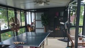 A spacious room with a ping pong table, a ceiling fan, and large windows offering a view of the outdoors. - RV Executive Home I - In Tranquil Setting, Indoor - In-ground Pool (Cottondale)