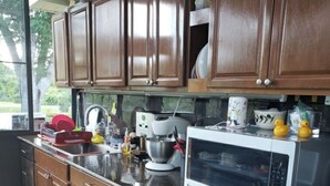 A kitchen with wooden cabinets, a microwave, an oven, and various kitchen items on the counter. - RV Executive Home I - In Tranquil Setting, Indoor - In-ground Pool (Cottondale)