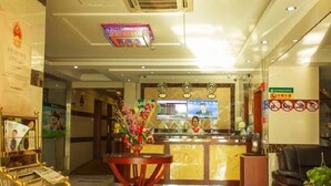 A hotel reception area with a reception desk, a waiting area with a sofa, and a wall-mounted television. - Greentree Inn Shanghai Baoshan District Gongfu New Village Metro Station Express Hotel (Shanghai)