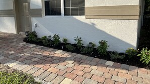A house with a white exterior, a front door, a window, and a brick pathway leading to the entrance. - Lovely Private Cottage, less than 5 miles to the beach!!! (Naples)